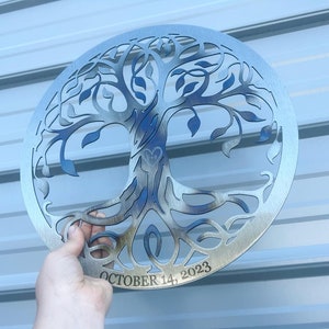 Peut inclure: Une d&eacute;coration murale en m&eacute;tal argent&eacute; en forme d'arbre de vie avec un motif de c&oelig;ur au centre et la date "OCTOBER 14, 2023" inscrite en dessous.