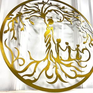 Puede incluir: Una decoraci&oacute;n de pared de metal dorado en forma de &aacute;rbol de la vida con una familia de tres figuras de pie sobre las ra&iacute;ces. El &aacute;rbol tiene ramas y hojas intrincadas.