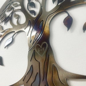 Peut inclure: Une d&eacute;coration murale en m&eacute;tal en forme d'arbre avec une d&eacute;coupe en forme de c&oelig;ur dans le tronc. Le c&oelig;ur porte les initiales "G+H" grav&eacute;es &agrave; l'int&eacute;rieur.