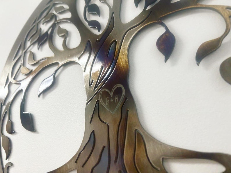 Peut inclure: Une d&eacute;coration murale en m&eacute;tal en forme d'arbre avec une d&eacute;coupe en forme de c&oelig;ur dans le tronc. Le c&oelig;ur porte les initiales "G+H" grav&eacute;es &agrave; l'int&eacute;rieur.