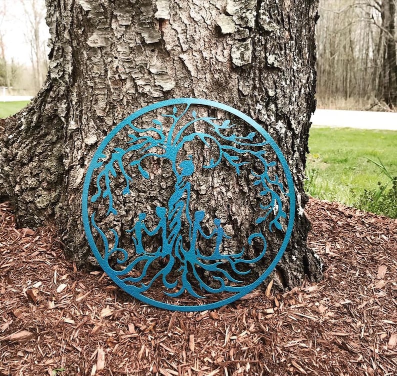 Puede incluir: Una decoraci&oacute;n de pared de metal azul en forma de &aacute;rbol de la vida con una familia de cinco figuras en el centro. El &aacute;rbol tiene ramas y ra&iacute;ces intrincadas.