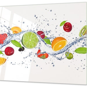 Peut inclure: Un assortiment coloré de fruits frais, comprenant un citron vert, une orange, un kiwi, des cerises et des fraises, est éclaboussé d'eau sur un fond blanc.