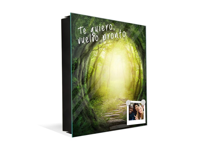 May include: A framed glass print with a photo of a path leading through a forest with a bright light at the end. The text "Te quiero, vuelvo pronto" is written on the print. A photo of three people is attached to the print with magnets.