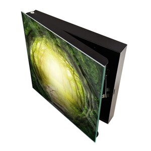 May include: A black framed picture with a green and yellow forest scene. The picture is open and the frame is visible.