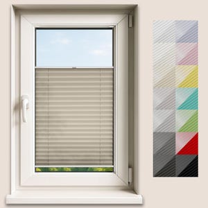 May include: A beige pleated blind is fitted within a white window frame. The blind is partially lowered, covering the window. A colour swatch of various pleated fabric shades is displayed to the right, showing different colour options.