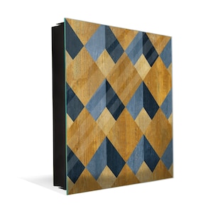 May include: A square wall art piece featuring a geometric pattern of blue and gold squares. The squares are arranged in a diagonal pattern, creating a sense of movement and depth. The background is a light wood grain.