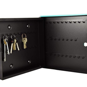 May include: A black metal key box with a turquoise door. The box has multiple hooks for hanging keys. The door is open and there are several keys hanging on the hooks.