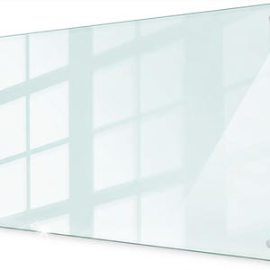 May include: A rectangular clear glass dry erase board featuring a smooth, transparent surface with polished edges. The board is mounted using four circular silver-toned metal standoffs positioned at each of the four corners for secure wall attachment.