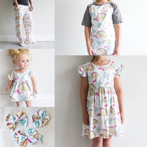 May include: A set of matching clothing featuring a white background with a print of colorful tacos, cacti, and red peppers. The set includes a pair of pants, a short-sleeved dress, a long-sleeved dress, and a doll-sized dress.