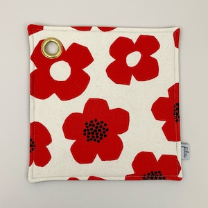 Peut inclure: Un porte-pot en tissu rouge et blanc avec un motif floral et un anneau en laiton. Le porte-pot porte l'inscription "idee".