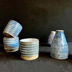 Peut inclure: Quatre tasses et vases en céramique avec un glaçage bleu et blanc. Les tasses et les vases ont un design texturé et ondulé.