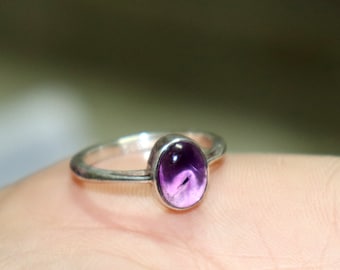 May include: A silver ring with a purple amethyst gemstone.