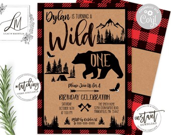 May include: A brown and red plaid invitation with a brown background. The invitation says "Dylan is turning one wild" with a black bear silhouette and the text "one" above it. The invitation also includes a campfire, mountains, and trees.