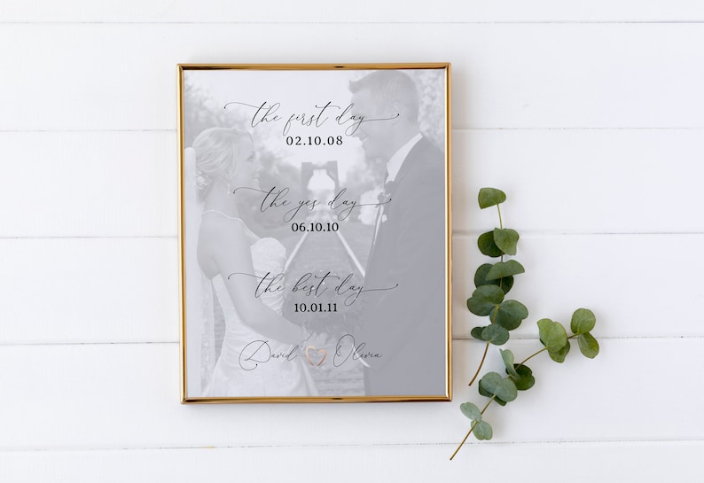 May include: A black and white photo of a couple in a gold frame. The photo is on a white wooden background. The text on the photo reads "The first day 02.10.08", "The yes day 06.10.10", "The best day 10.01.11", and "David & Olivia".
