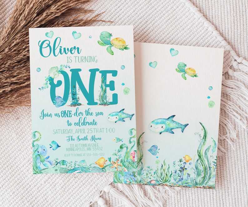 Peut inclure: Une carte d'invitation bleue et verte avec une illustration aquarelle d'une tortue de mer, d'un requin et d'autres cr&eacute;atures marines. Le texte sur la carte indique "Oliver a un an. Rejoignez-nous pour f&ecirc;ter &ccedil;a le samedi 25 avril &agrave; 13h00 chez les Smith 111 Autumn Avenue Minneapolis, MN 55432 RSVP au [num&eacute;ro de t&eacute;l&eacute;phone]"