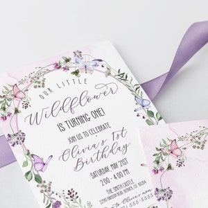 May include: A white invitation card with a watercolor floral wreath and butterflies. The text reads "Our Little Wildflower is Turning One! Join us to celebrate Olivia's 1st Birthday, Saturday, May 21st, 2:00 - 4:00 PM, The Smith Castle, 2201 Windsor Rd, Denver, CO 80204, RSVP to Olivia's mom (555) 555-5555".