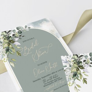 May include: A green and white floral design with a gold arch on a light blue background. The text reads "Join us for a Bridal Shower to honor Olive Smith, Saturday, September 18th at 2:00 pm, the smith bytre, 111 Autumn Avenue, Minneapolis, MN 55432, registered at Ange".