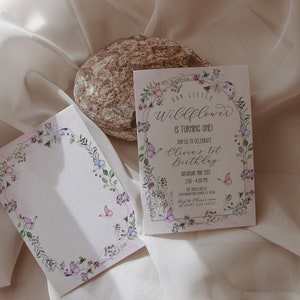 May include: A floral-themed invitation with butterflies and greenery surrounding the text "Our Little Wildflower is Turning One!"  Join us to celebrate Olivia's 1st Birthday, Saturday, May 2021, 2:00 - 4:00 PM. The Sprout Little, 123 Main Street, Anytown, USA. RSVP: 555-555-5555.