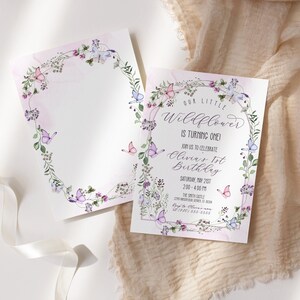 May include: A floral-themed birthday invitation with a watercolor design featuring butterflies and flowers. The text reads "Our Little Wildflower is turning one! Join us to celebrate Olivia's 1st Birthday. Saturday, May 21st, 2:00 - 4:00 PM. The Smith Castle, 1234 Smith Street, Anytown, CA 12345. RSVP to 123-456-7890."