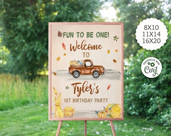 May include: A framed sign with a fall theme, featuring a brown truck carrying pumpkins. Text includes "FUN TO BE ONE! Welcome to Tyler's 1st Birthday Party." Sizes available: 20x25, 28x35, and 41x51 cm. The sign is displayed on a wooden easel.