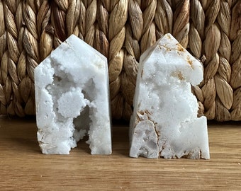 May include: Two white crystal bookends with a rough, textured surface. The bookends are shaped like a house and have a natural, organic look.