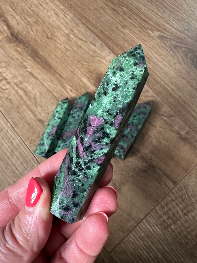 May include: A collection of green, pink and black gemstone points. The points are polished and have a smooth, shiny finish.