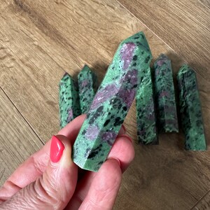 May include: A collection of green, pink and black gemstone points. The points are polished and have a smooth, shiny finish.