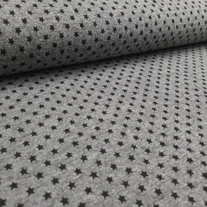 Könnte beinhalten: Grauer Stoff mit einem schwarzen Sternenmuster. Der Stoff ist weich und hat eine subtile Textur.