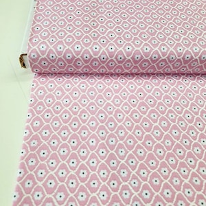 Könnte beinhalten: Rosafarbener Stoff mit einem weißen und schwarzen Blumenmuster. Das Muster ist ein sich wiederholendes Design aus kleinen weißen Blüten mit schwarzen Zentren, die in einer Diamantform angeordnet sind.