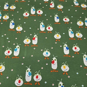 Könnte beinhalten: Grüner Stoff mit einem sich wiederholenden Muster aus skurrilen, cartoonartigen Kreaturen. Jede Kreatur hat einen weißen Körper, bunte Augen, eine rote oder blaue Nase und orangefarbene Füße. Kleine, farbige Punkte sind über den Hintergrund verstreut.