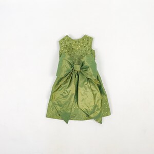 May include: A green sleeveless dress with a large bow at the waist and a beaded bodice.