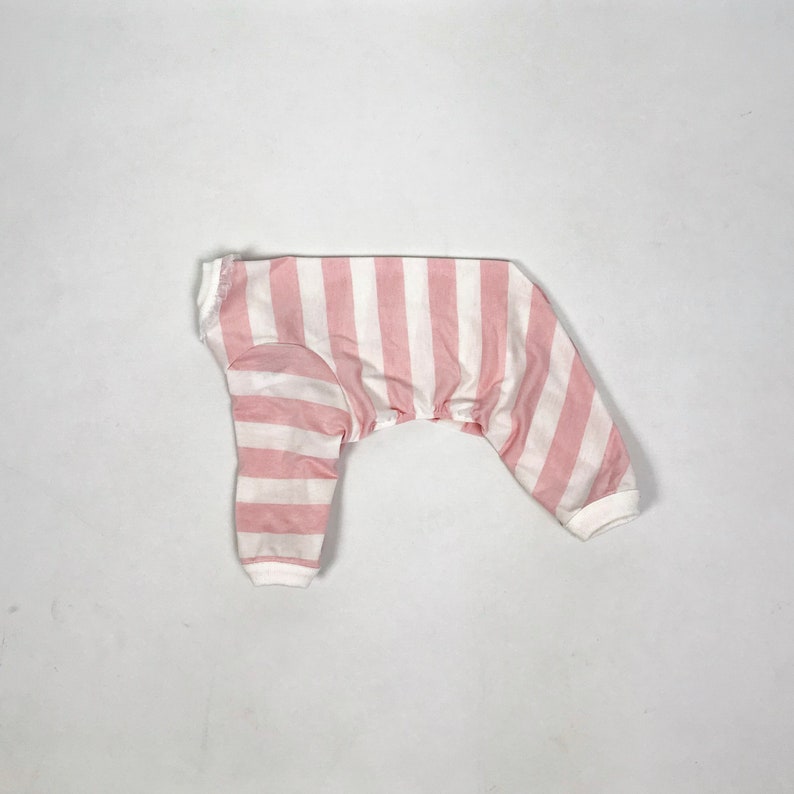 The flatlay of the Pink & White Striped onesie shows white cuffs on the hems and a frill around the neckline.