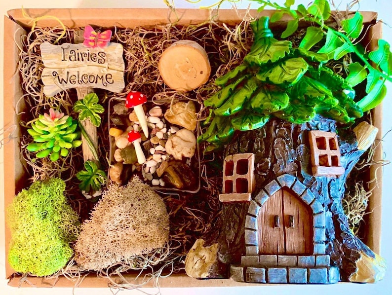 Pode incluir: Uma cena de jardim de fadas em miniatura com uma placa de madeira que diz "Fairies Welcome", uma pequena casa na &aacute;rvore com uma porta e janelas, uma suculenta verde e uma pequena pilha de pedras.