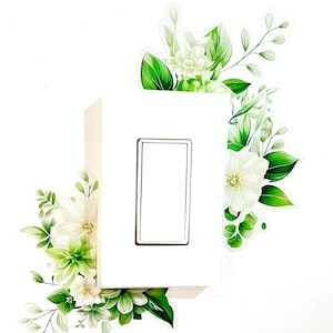Peut inclure: Un interrupteur blanc avec un motif floral blanc. Les fleurs sont dans les coins de l'interrupteur et sont vertes et blanches.