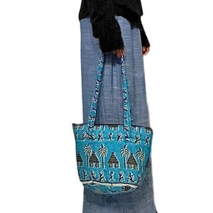 Peut inclure: Un sac fourre-tout matelassé de couleur bleu turquoise vif arborant un motif répétitif de palmiers, de petites huttes et de silhouettes stylisées en brun foncé. Le sac est doté de deux anses assorties et d'une base rectangulaire.