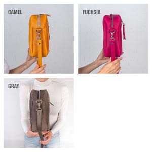 May include: A set of three leather crossbody bags in camel, fuchsia, and gray. Each bag has a rectangular shape, a zipper closure, and a long strap. The bags are displayed against a white background.