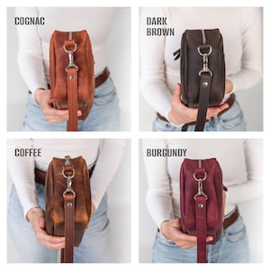 May include: Four leather crossbody bags in cognac, dark brown, coffee, and burgundy. Each bag has a zipper closure, a detachable strap, and silver-tone hardware. The bags are rectangular and have a distressed finish.
