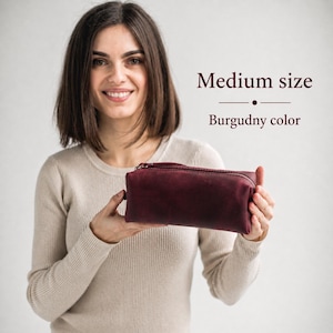 May include: A burgundy-colored, medium-sized pencil case with a zipper closure. The text on the image reads "Medium size" and "Burgundy color".
