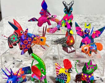 Pode incluir: Uma coleção de 10 figuras de animais de madeira pintadas à mão. As figuras são coloridas de forma brilhante e apresentam detalhes intrincados. Os animais incluem um galo, um gato, um elefante, um unicórnio, um pássaro, uma borboleta, um caranguejo, um burro, um cavalo e um peixe.