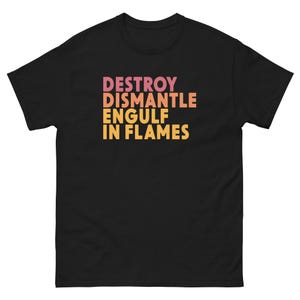 Puede incluir: Camiseta negra con la frase "DESTROY DISMANTLE ENGULF IN FLAMES" en degradado de rosa, naranja y amarillo. El texto está centrado en la parte delantera de la camiseta.