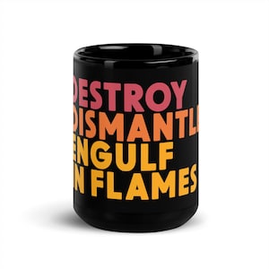 Könnte beinhalten: Schwarze Keramik-Tasse mit den Worten "DESTROY DISMANTLE ENGULF IN FLAMES" in einem Farbverlauf aus Pink, Orange und Gelb. Die Tasse ist zylindrisch und hat eine glänzende Oberfläche.