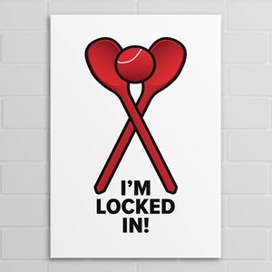 Peut inclure: Une affiche blanche avec un graphisme rouge de deux cuillères croisées et d'une balle, avec le texte "I'M LOCKED IN !" en noir. L'affiche est accrochée à un mur de briques blanches.