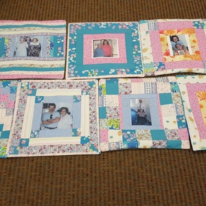 May include: Seven square quilted pillow covers with different patterns and colors. Each pillow cover features a framed photo of a couple. The pillow covers are made with a variety of fabrics, including floral prints, plaid, and solid colors.
