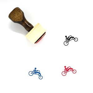Puede incluir: Un sello de goma de madera con una ilustración en negro, azul y rojo de una persona montando una bicicleta reclinada.