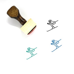 May include: Wooden stamp with a black and white line drawing of a person skiing down a slope. The stamp is on a white background.