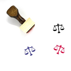 Könnte beinhalten: Holzstempel mit einem schwarzen Stempelkissen und einem Motiv einer Justitia-Waage. Die Justitia-Waage ist auch in Blau und Rot dargestellt.
