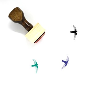 May include: A wooden stamp with a brown handle and a rectangular base. The stamp's imprint is a stylized bird in black, teal, and blue. The stamp is angled, showing the red ink pad. The image is on a white background.