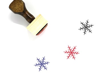 May include: A wooden stamp with a snowflake design. The stamp is on a white background. There are three snowflake impressions in different colors: black, red, and blue.