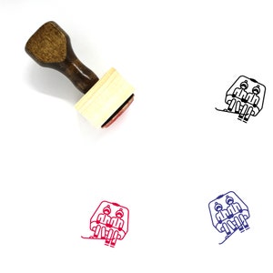 以下が含まれることがあります： 茶色のハンドルと長方形の木製ブロックが付いた木製ゴム印。スタンプには、スキーリフトに乗っている2人の人の黒の線画が描かれています。