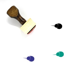 May include: A wooden rubber stamp with a brown handle and a rectangular base. The stamp features a black silhouette of a horseshoe crab. The image also shows the stamp imprint in black, blue, and green.
